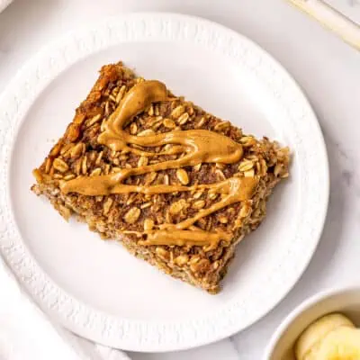 Slice of banana bread baked oats on a white plate.