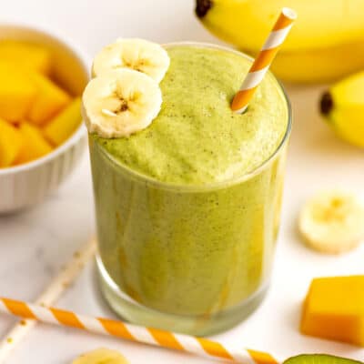 Banana Mango Kiwi Smoothie with banana slices and a straw.