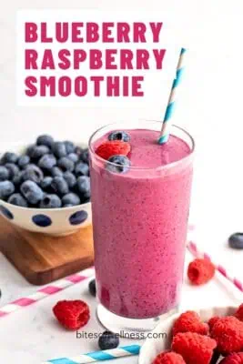 Glass filled with blueberry raspberry smoothie, a blue straw in the glass.