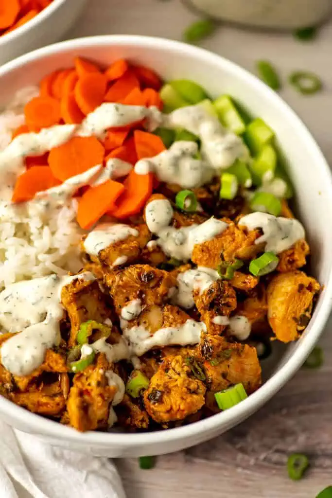 Ranch dressing drizzled over buffalo chicken rice bowl.