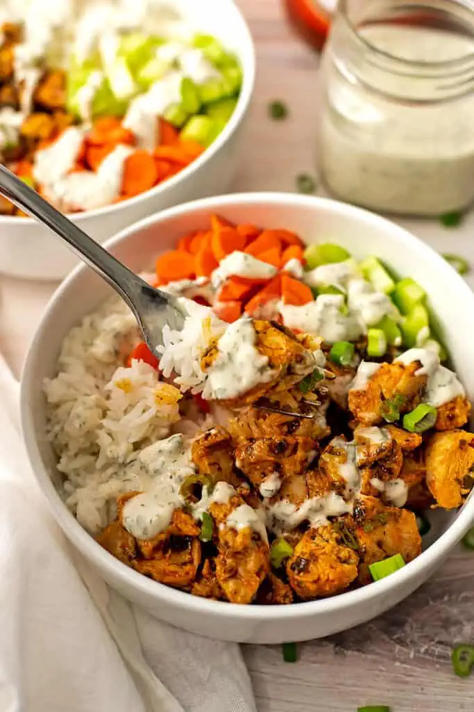 Fork in bowl of buffalo chicken rice bowl with ranch dressing.