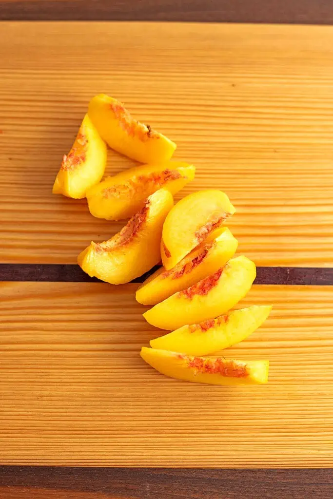 Peaches sliced up on a cutting board.