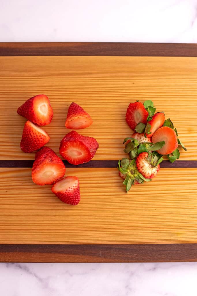 Strawberries cut up on a cutting board.