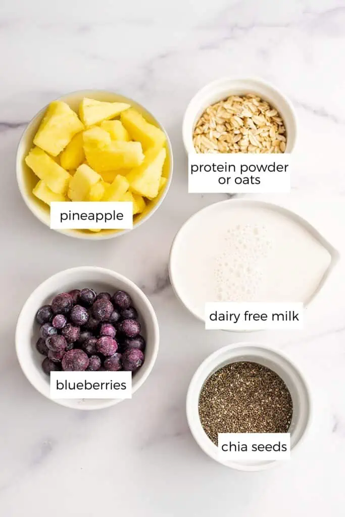 Pineapple blueberry smoothie ingredients separated into white ramekins.