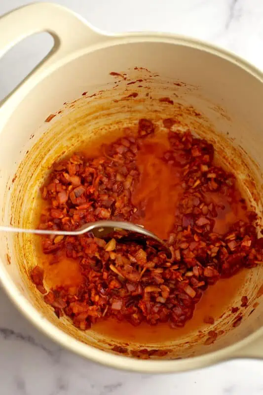 Vegetable broth added to tomato paste and veggies in pot.