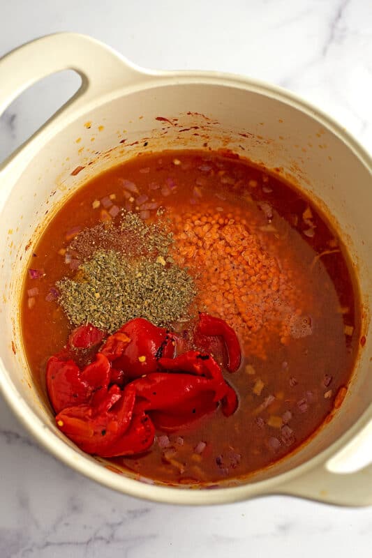 Roasted red peppers, red lentils and spices in pot with vegetable broth.