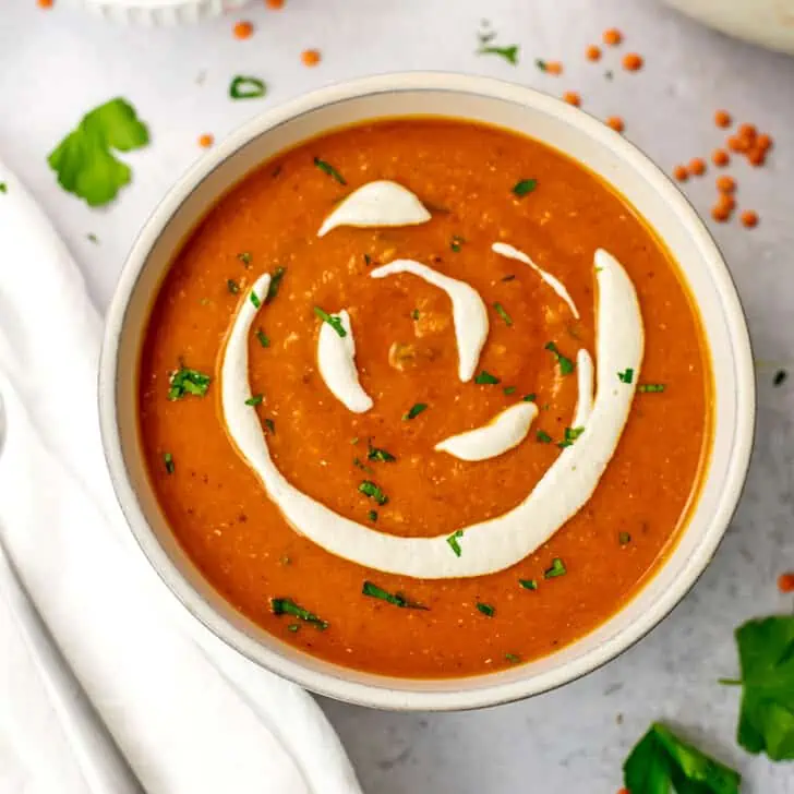 Cashew cream drizzled over red pepper lentil soup.