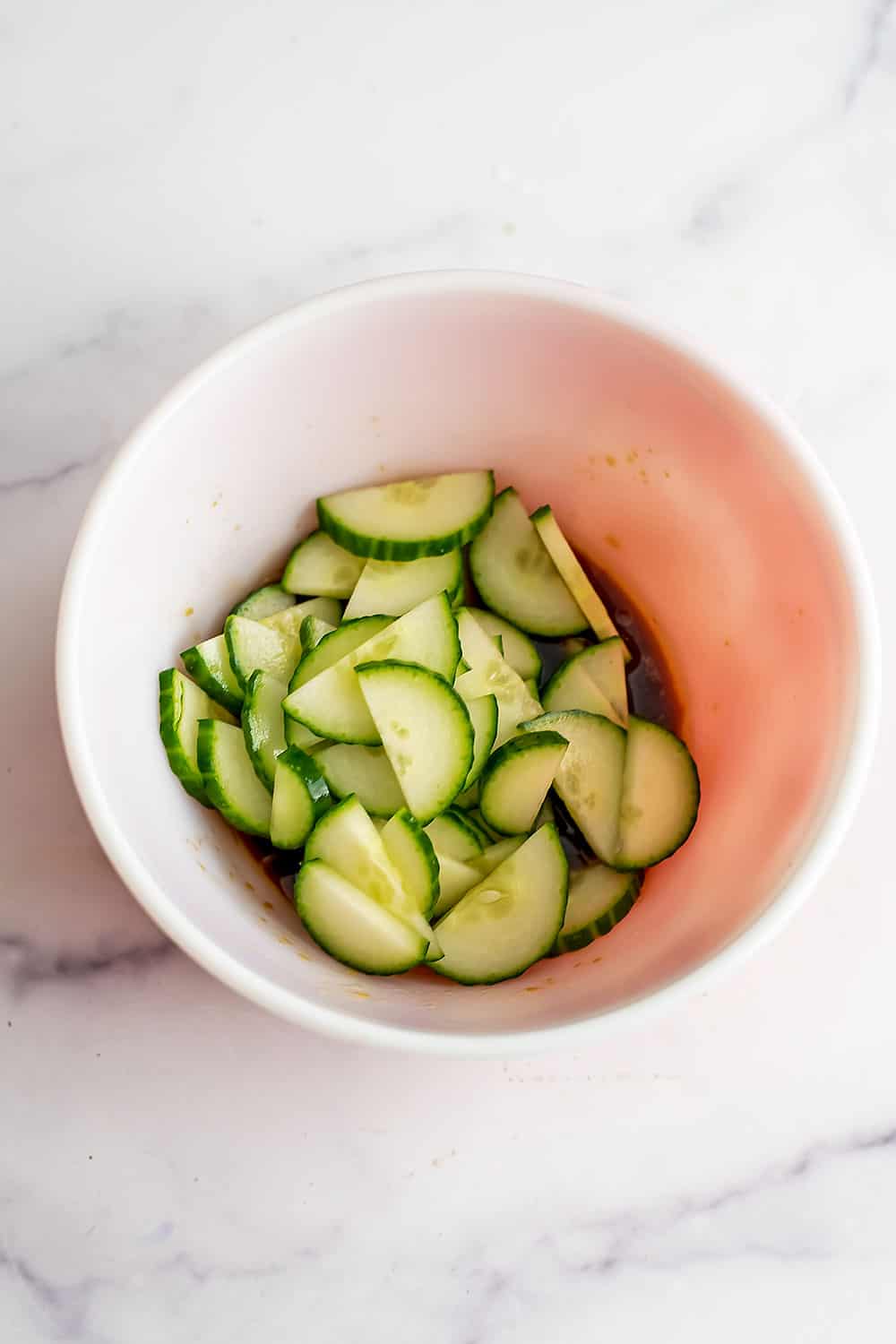 Sliced cucumber in a bowl before marinating.