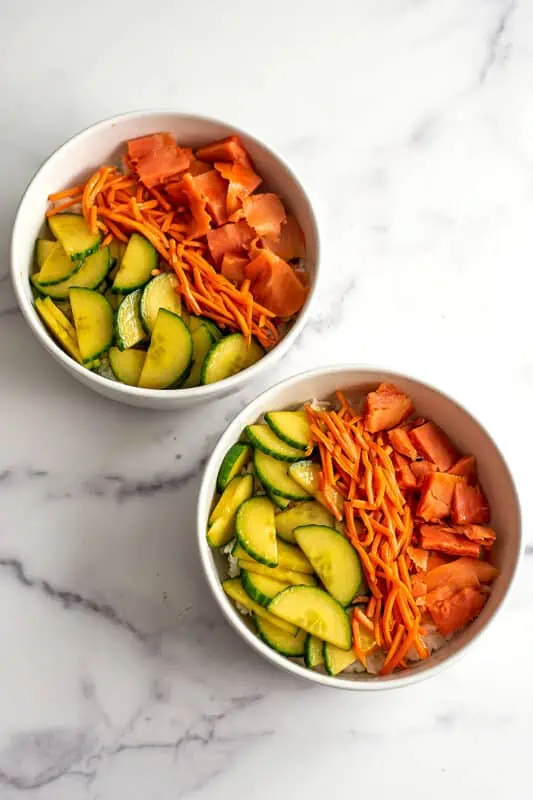 Two smoked salmon bowls on a marble countertop.