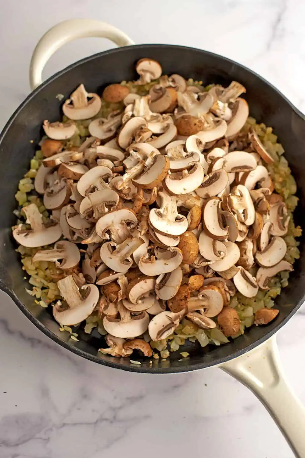 Sliced mushrooms added to skillet before cooking.