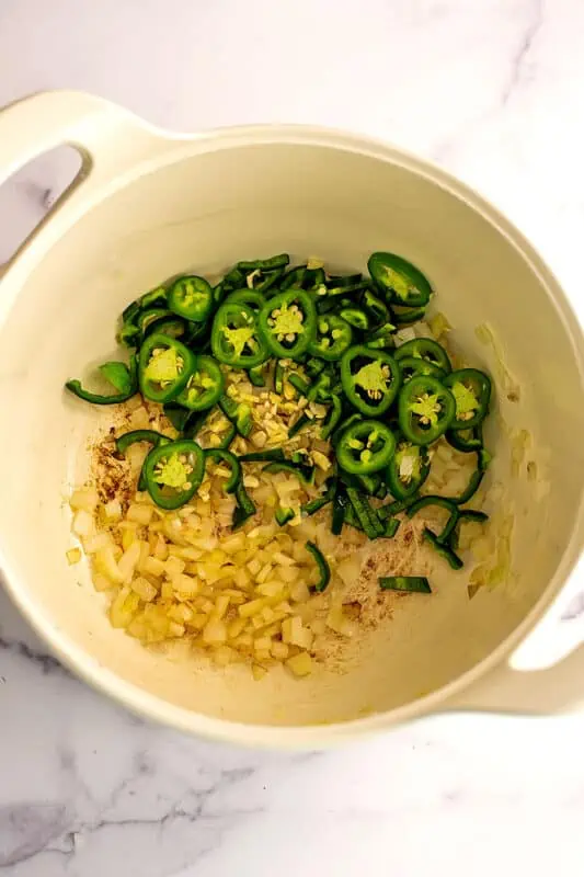 Jalapeno and poblano peppers added to pot with cooked onions.