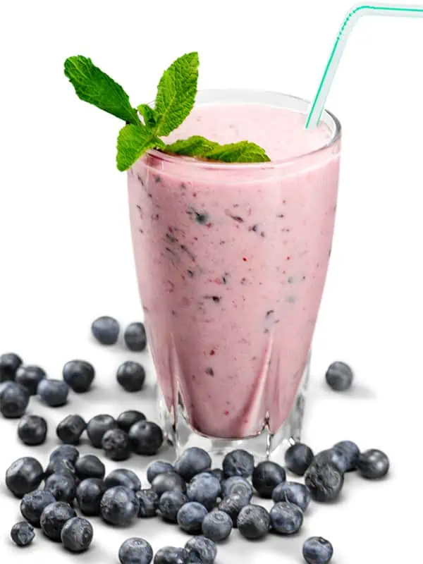 A blueberry smoothie surrounded by blueberries on a white table.