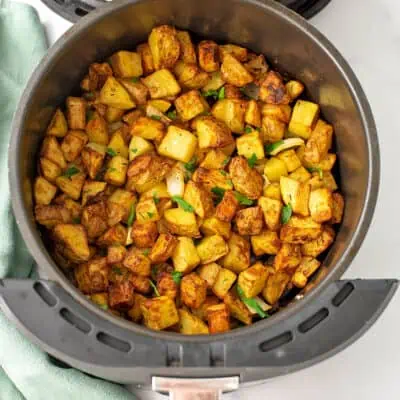 Air fryer basket with roasted potatoes and onions.