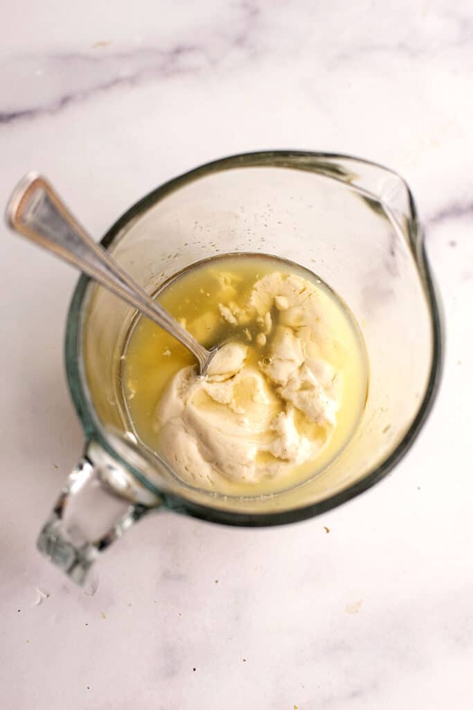 Ingredients to make lemon yogurt topping in a glass measuring cup before stirring.