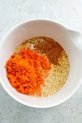 Shredded carrots, oats, and spices added to bowl with ground flax mixture. 