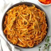 Large grey bowl filled with carrot sauce pasta.