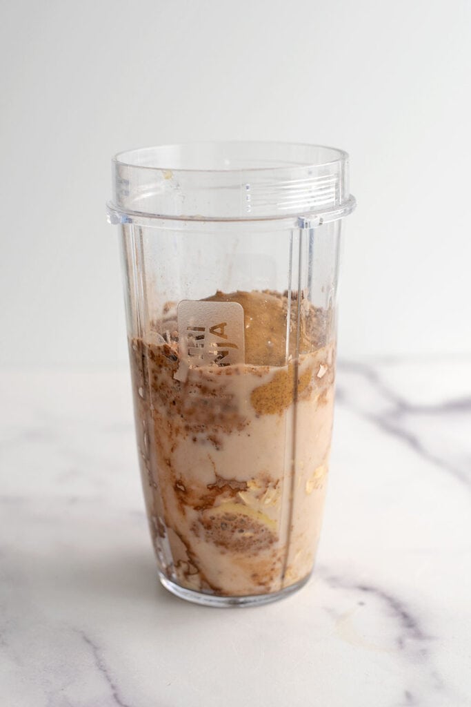 Chocolate banana oat smoothie ingredients in a blender cup before being blended.