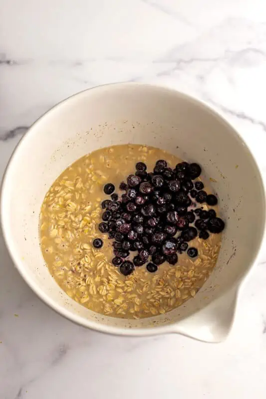 Frozen blueberries added to the oatmeal mixture in large bowl.