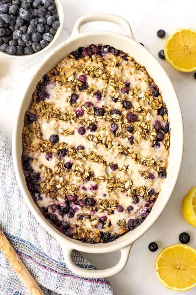 Lemon blueberry baked oats in a casserole dish, lemon slices on the side.