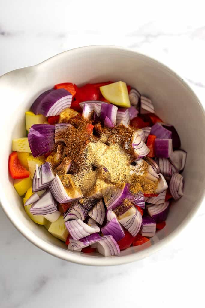 Spices on top of a bowl of chopped vegetables.
