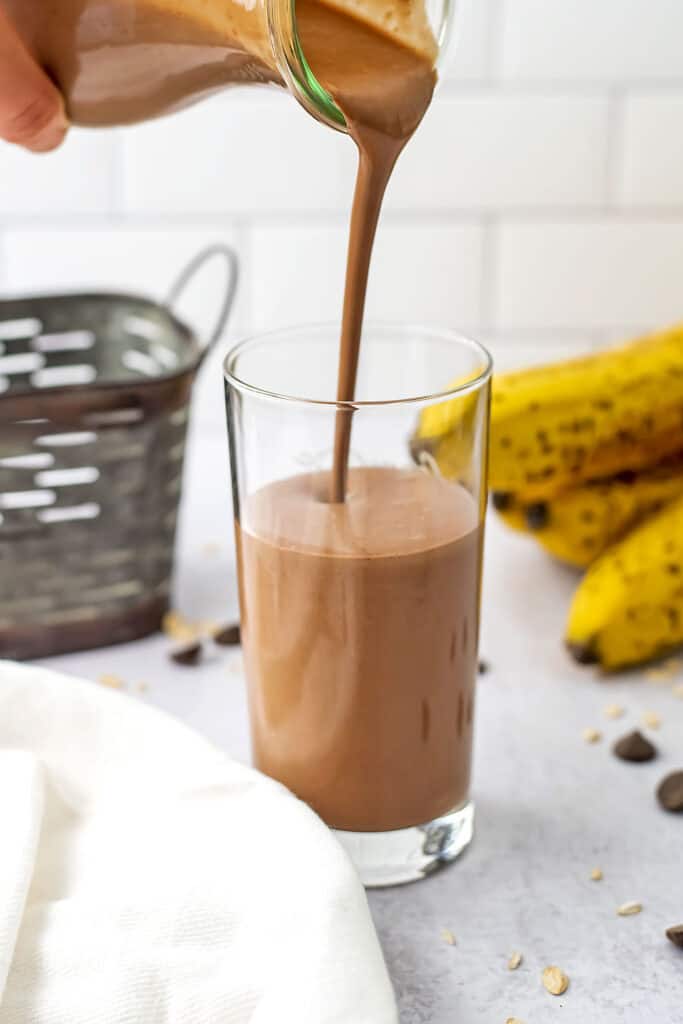 Oat chocolate smoothie being poured into a glass.