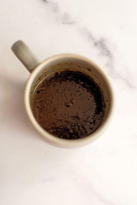 Coconut sugar and avocado oil stirred together in mug.