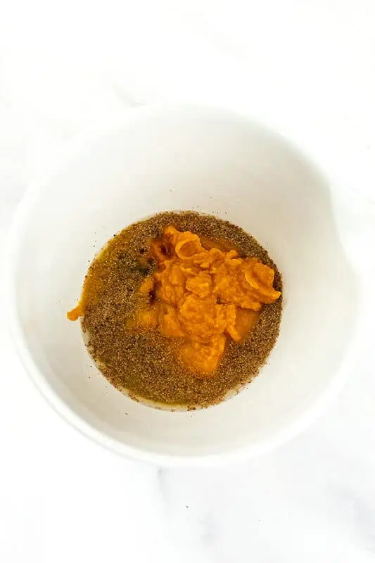 Pumpkin puree, ground flax, water and maple syrup in a large white bowl.