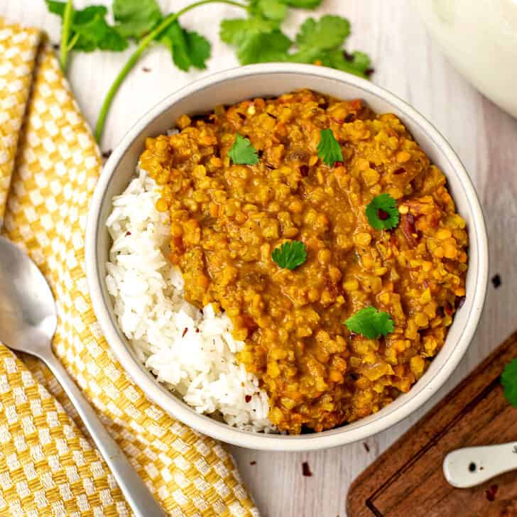 Rice and lentil curry in a bowl with a spoon on the side.