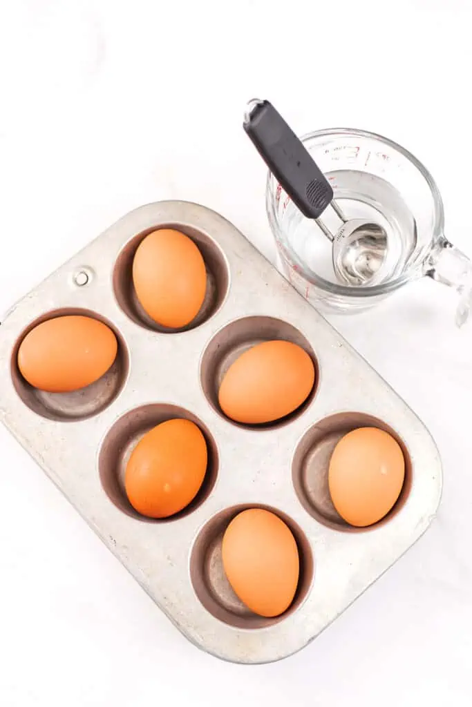 Eggs in the shell resting in a muffin tin.