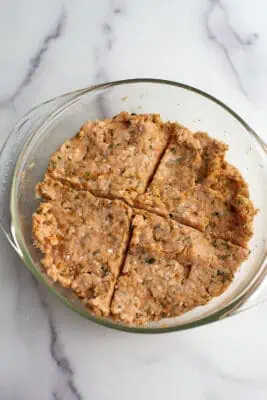 Ground chicken mixture divided in 4 equal parts in glass bowl.