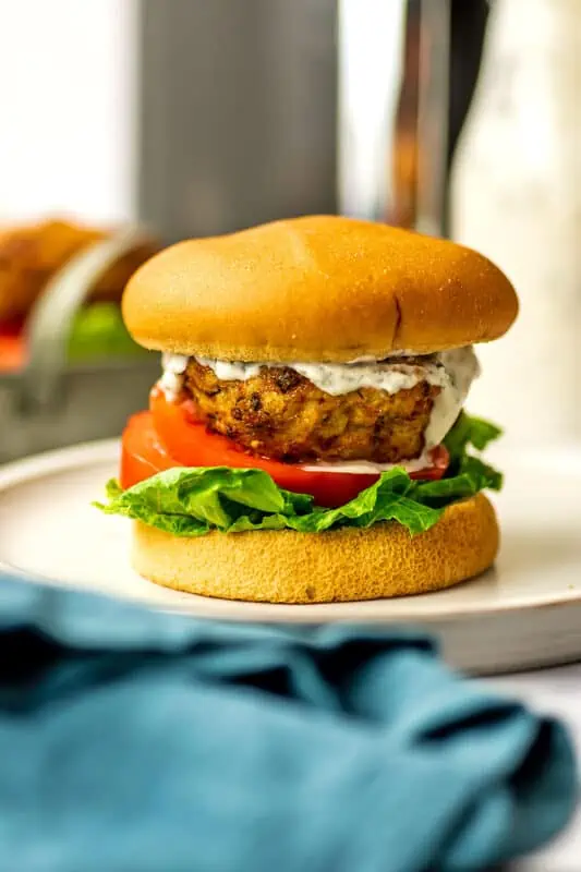 Air fryer chicken burger on a bun with ranch dressing, lettuce and tomato.