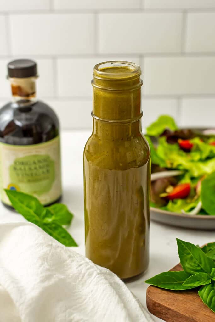 Basil balsamic dressing in a bottle with white napkin.