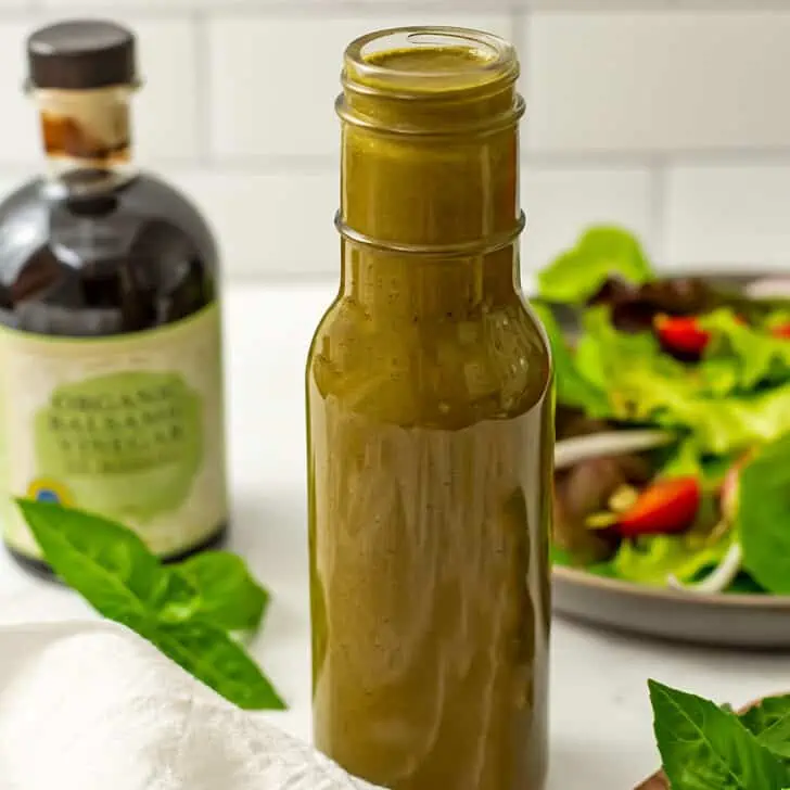 Basil balsamic dressing in a bottle with white napkin.