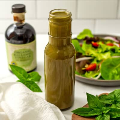 Balsamic basil vinaigrette in glass bottle with balsamic vinegar in back.