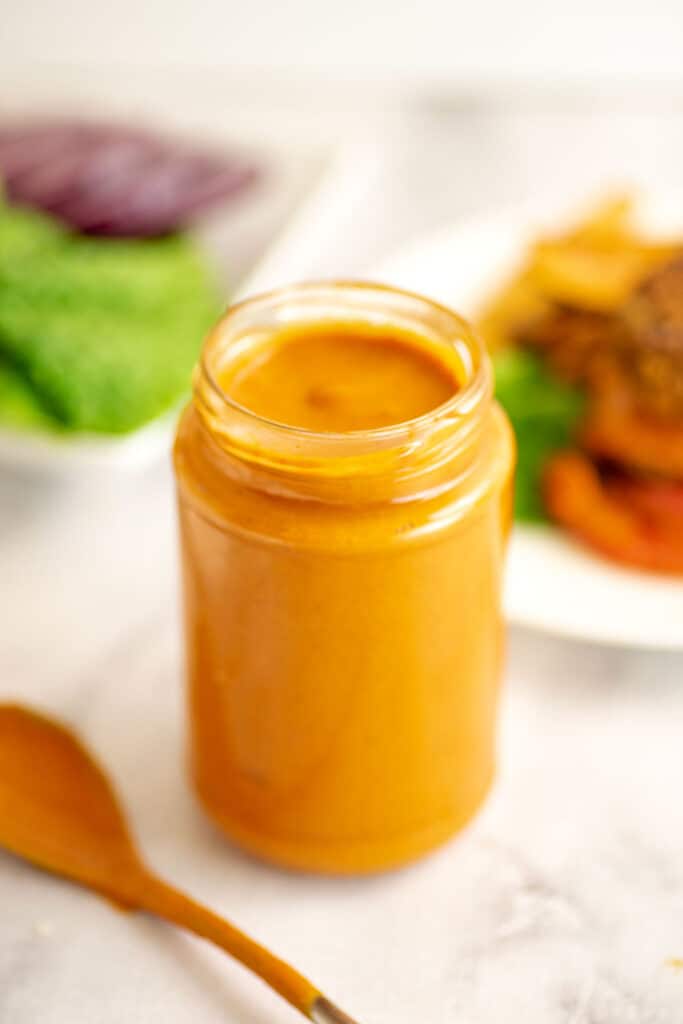 Glass jar filled with chipotle tahini sauce.