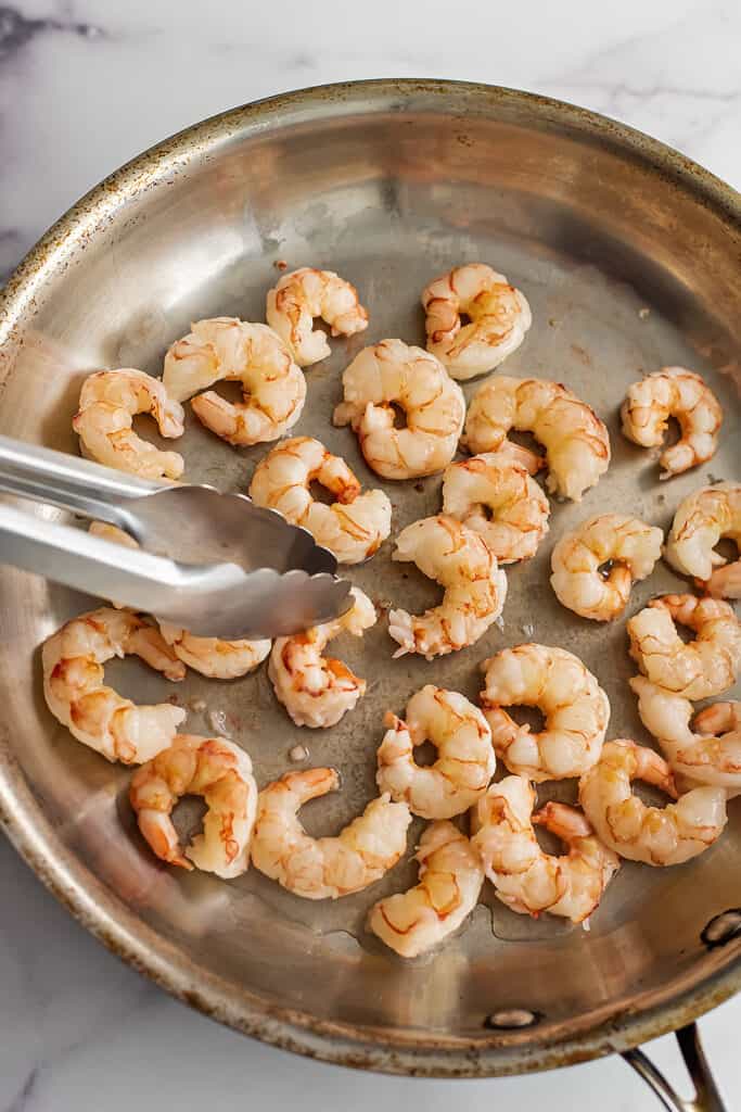 Shrimp being flipped after cooking 2-3 minutes.