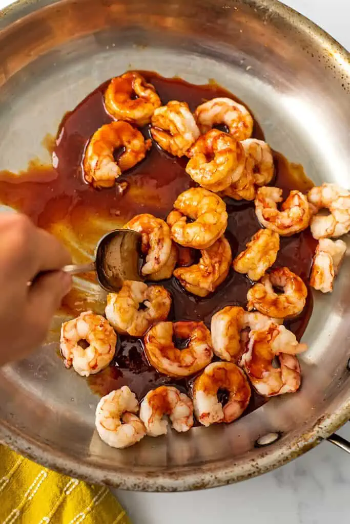 Honey sriracha sauce being stirred in with the shrimp.