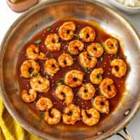 Spicy honey shrimp in skillet with sesame seeds on top.