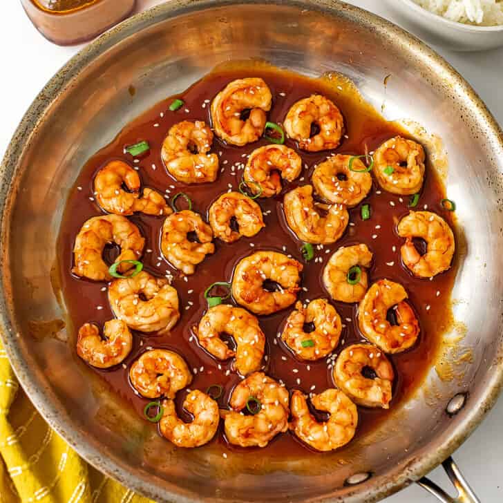 Spicy honey shrimp in skillet with sesame seeds on top.
