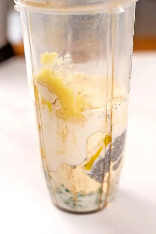 Ingredients to make mango kale smoothie in blender cup before blending.