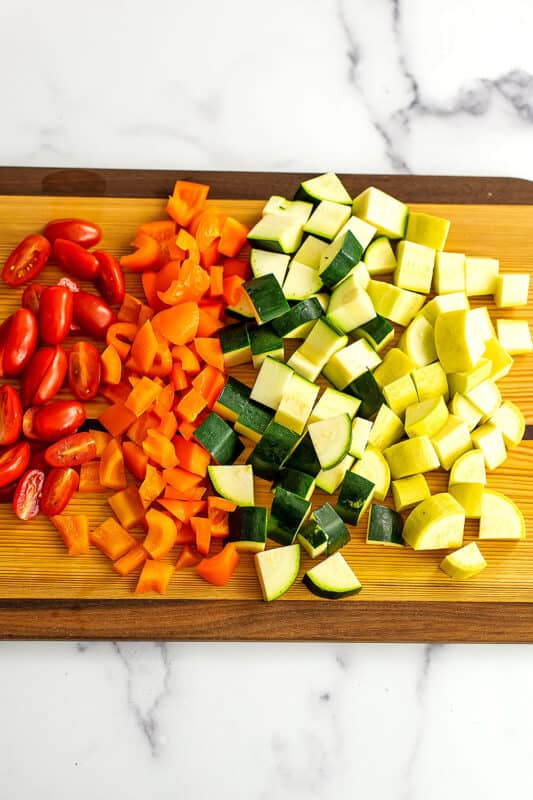 Chopped vegetables on a wood chopping board.