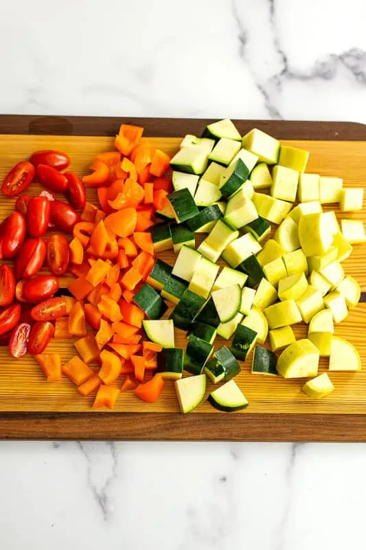 Chopped vegetables on a wood chopping board.