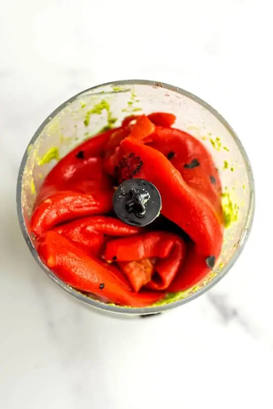 Roasted red peppers added to food processor with basil pesto.