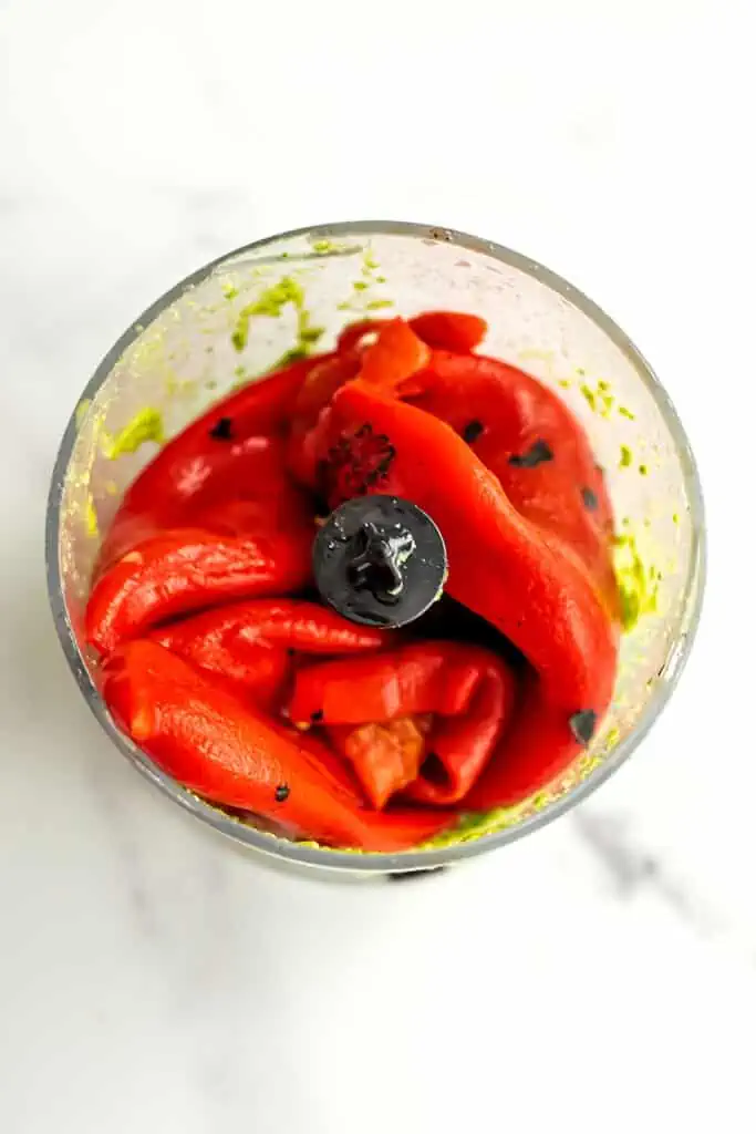 Roasted red peppers added to food processor with basil pesto.