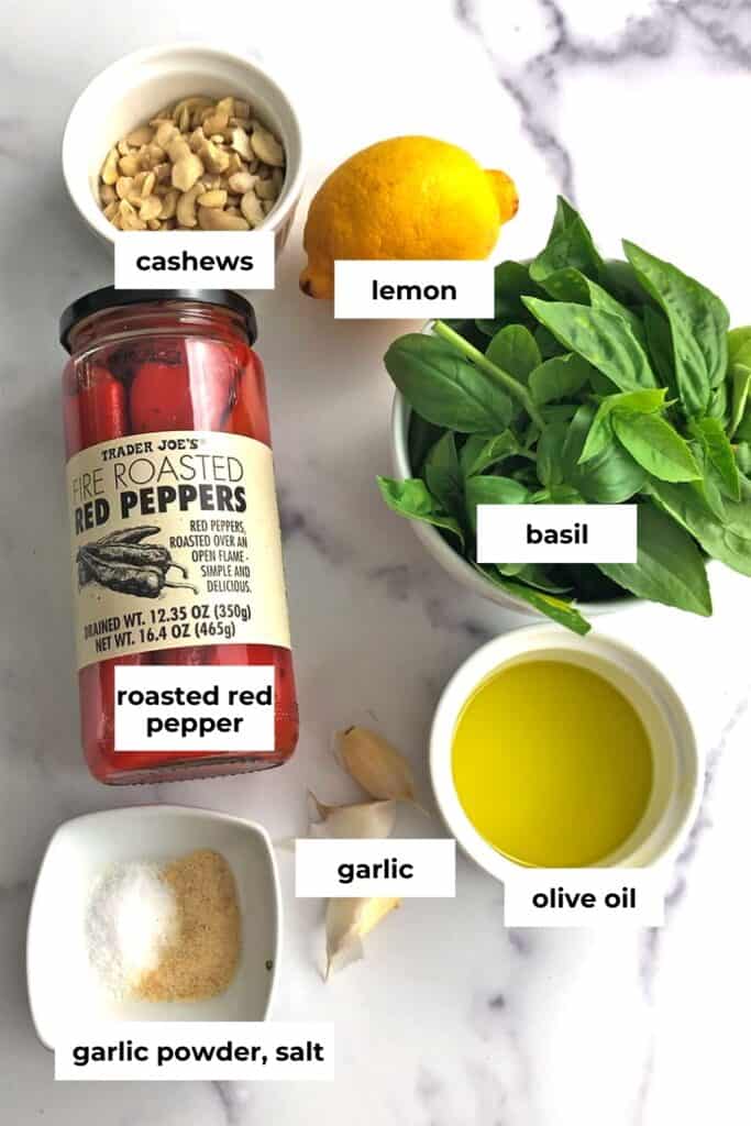 Ingredients to make red pepper pesto on a marble countertop.