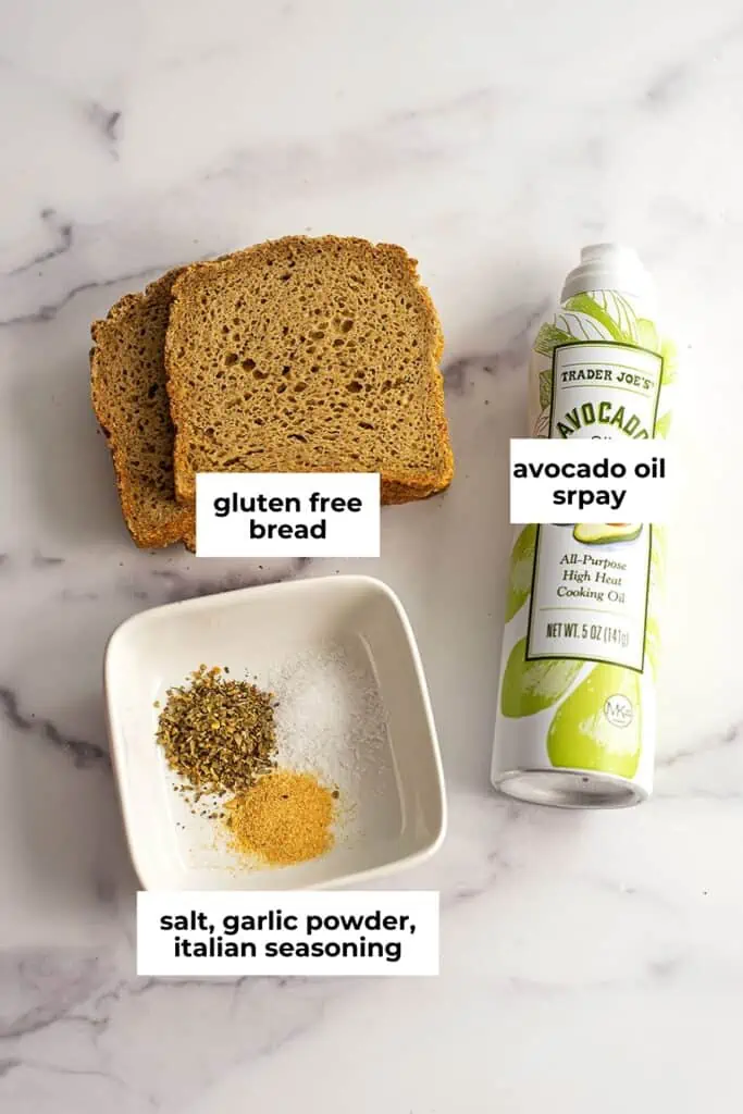 Spices, avocado oil spray and bread on marble countertop.