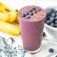 Blueberry banana spinach smoothie topped with blueberries and peanut butter drizzle.
