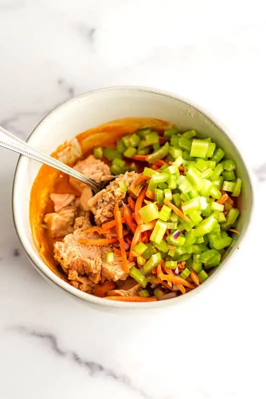 Bowl filled with buffalo sauce, tuna and chopped veggies.