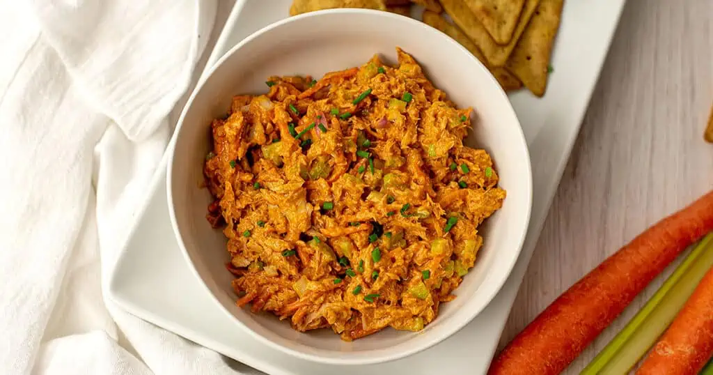 Buffalo tuna salad in a white bowl sitting on a white table.