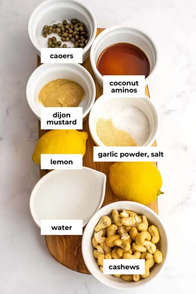 Cashew caesar dressing ingredients in bowls on wooden cutting board.